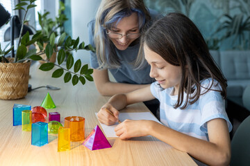 Two schoolgirls aged 11 and 13 working together on a STEM geometry project, exploring shapes and spatial concepts through hands-on learning and collaborative classroom activity.