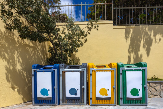 Colorful recycling bins and labeled trash containers placed on the street. Waste separation bins used for eco-friendly garbage disposal - Powered by Adobe