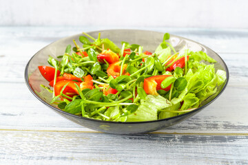 Fresh vegetable salad with micro greens and red pepper in a transparent bowl. Concept of healthy nutrition using for cookbook or food blog.