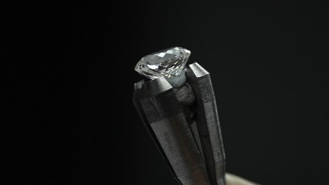 Macro close-up of a sparkling diamond held in a dop stick being rotated for inspection and polishing