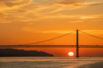 Sunset view of the 25 de Abril Bridge in Lisbon over the Tagus River. Perfect for postcards magnets travel guides magazines websites and tourism materials.