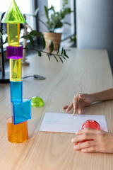 Two schoolgirls studying 3D geometric shapes during math class, drawing and discussing figures together as part of interactive STEM learning and teamwork activity in a modern classroom.