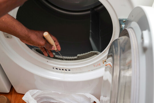 A black man cleaning out a dryer vent with a brush
