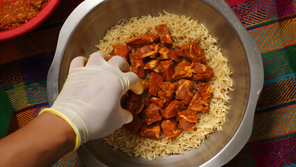 Overhead shot of gloved hands arranging marinated meat on rice, vibrant food preparation.