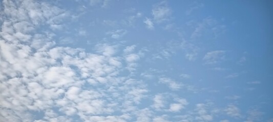 Background with clouds on blue sky. Sky view. Beautiful sunny sky. Clouds on blue sky. Sun shining through the puffy clouds.
