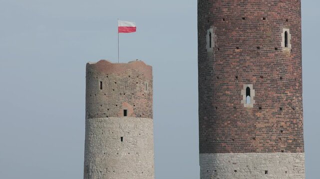 The Polish flag proudly waves atop the historic tower of Checiny Castle in Poland, symbolizing national heritage and pride against a clear sky.