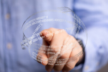 Close-up of a hand interacting with a transparent sphere displaying code, representing digital technology and data.