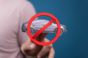 Image of a hand holding a no car sign, symbolizing driving restrictions or prohibitions.