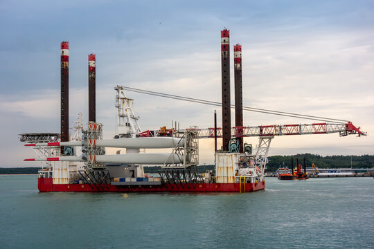 Offshore Wind Turbine Installation Vessel with Giant Crane and Turbine Blades at Sea. Renewable Energy Logistics, Industrial Maritime Engineering and Green Energy Transition Concept