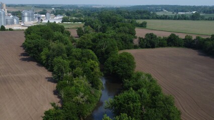 Aerial view of rural landscape with river and silos.