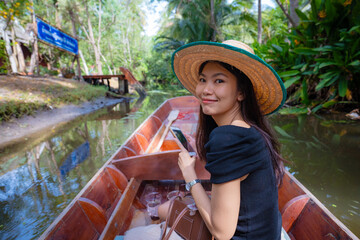 Fototapeta premium Beautiful asian woman travel on wooden boat in floting market tropical forest river travel
