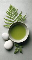 Calm, serene spa scene.  Green liquid in bowl, fern leaves, stones