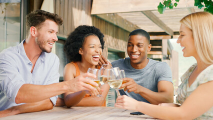 Group Of Smiling Multi-Cultural Friends Outdoors At Home Drinking Wine Together