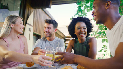 Group Of Smiling Multi-Cultural Friends Eating Breakfast Outdoors At Home