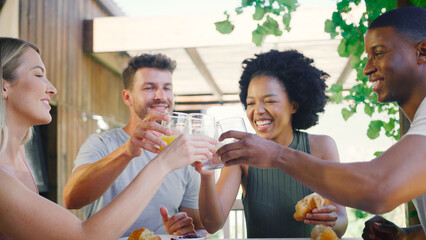 Group Of Smiling Multi-Cultural Friends Eating Breakfast Outdoors At Home