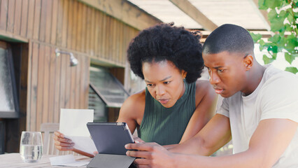 Worried Couple Using Digital Tablet At Home To Check Domestic Finances