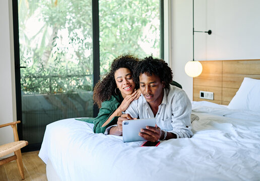 Portrait of a lovely young couple together holding a tablet in bed at home