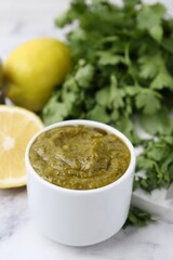 Tasty sauce with cilantro and other ingredients on white marble table, closeup
