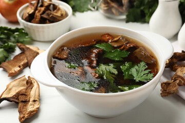 Tasty soup with mushrooms and parsley in bowl on white table, closeup