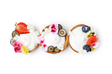 Delicious dessert. Tartlets with cream, berries and flowers isolated on white, top view