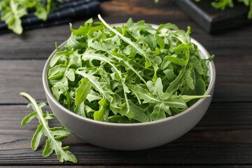 Fresh ripe green arugula leaves on dark wooden table, closeup