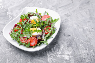 Tasty salad with arugula, vegetables, egg and seeds on grey table, closeup. Space for text