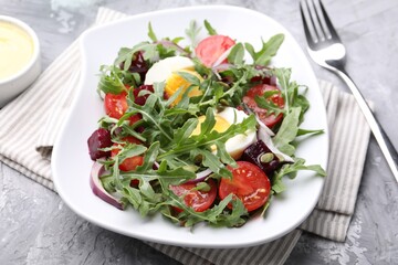Tasty salad with arugula, vegetables, egg and seeds on grey table, closeup