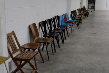 Image of many chairs lined up against a white wall. Perfect for vintage, retro, or minimalist designs.