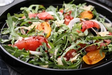 Tasty salad with arugula, cheese, grapefruit, vegetable and balsamic sauce on dark wooden table, closeup