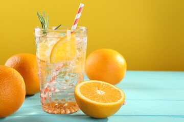 Refreshing soda water with ice and orange on light blue wooden table, closeup. Space for text