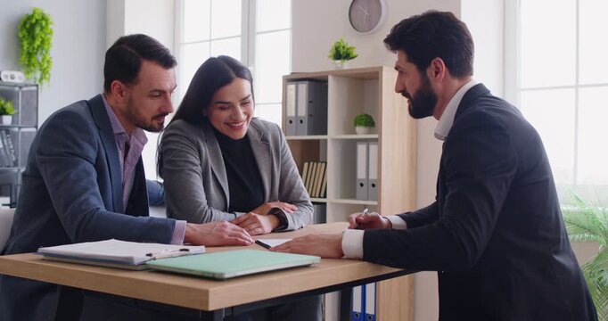 Realtor meeting with couple, looking through contract and other documents, considering variation, making presentation offer, meeting in office. Male financial advisor giving consultancy