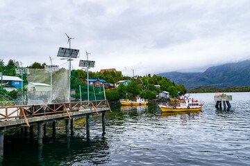 Fishing boats docked at small chilean patagonia village harbor with renewable energy infrastructure