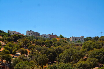 Naklejka premium Mediterranean hillside village with white houses and green trees under blue sky