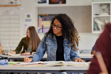 Smiling multiethnic student writing during lesson