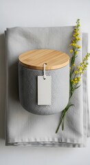 Still life of a textured jar with flowers and a blank paper tag