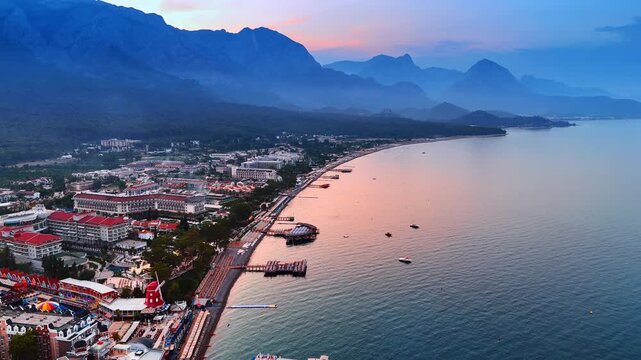 View on the seaside resort town in Antalya Province, Turkey. Beautiful dusk time in Kemer colored pink. Aerial perspective.
