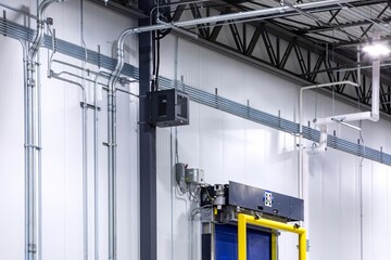 Steel support beams in and and electrical tubing on walls in refrigerated warehouse