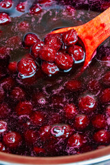 Preparing freshly picked red cherries with sugar to make cherry jam in a saucepan with a wooden spoon, closeup. Cooking berries marmalade, home cooking
