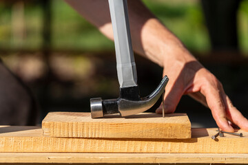 A worker using a hammer nail puller to pull a nail out of a wooden board, closeup. Hand tool for working. Multifunction shockproof steel hammer and nail