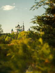 Naklejka premium Picturesque Orthodox Church atop a Hill, Surrounded by Lush Greenery and Sunlight