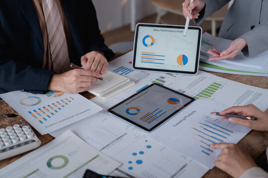 Business team analyzing financial documents, charts and graphs using digital tablets during a meeting to discuss company's performance and sales using data visualization tools