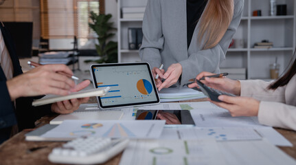 Business colleagues working together and analyzing financial figures on electronic tablet during a meeting at office, evaluating company performance and discussing new business plan