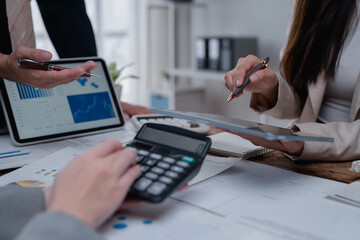 Fototapeta premium Business people are working together, analyzing financial data on digital tablet and using calculator during a meeting to discuss company financial performance