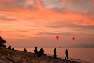 Fototapeta premium silhouettes of kids with baloons on the beach at sunset
