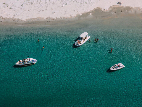 Crystal clear waters with boats and people enjoying a summer day at the beach