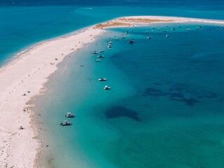 Clear blue waters and sandy beaches attract boaters to a picturesque coastal area during a sunny day