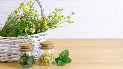Medicinal chamomile in a white woven basket and glass jars with chamomile and mint