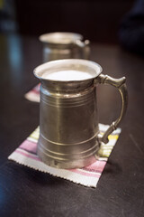 Vintage Japanese metal beer mugs filled with beer, photographed on a dark wooden table with soft lighting and retro styling