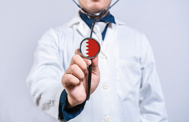 Doctor hands holding stethoscope with Bahrain flag. Bahrain health and care concept