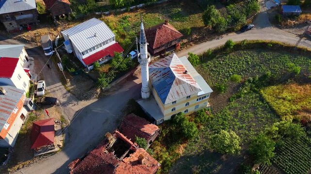 A peaceful 4K aerial view of a village mosque with a waving Turkish flag in Kurtlu K&ouml;y&uuml;, Boyabat, Sinop. Traditional rural life and architecture meet nature in this beautiful countryside footage.